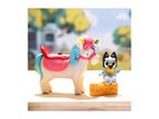 Bluey and a unicorn toy set on a wooden surface with a blurred outdoor background
