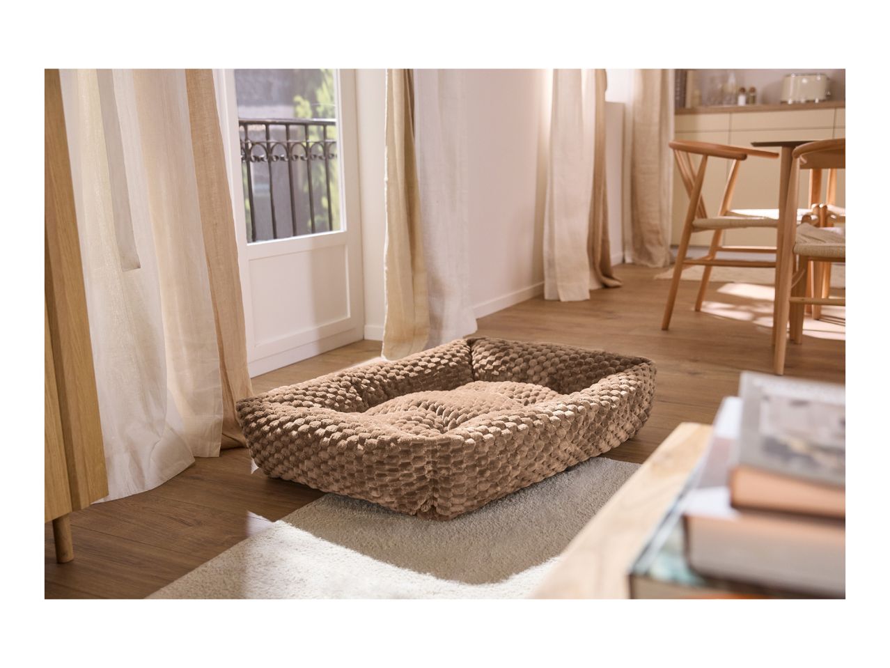 Plush brown dog bed on a rug in a bright, modern living room.