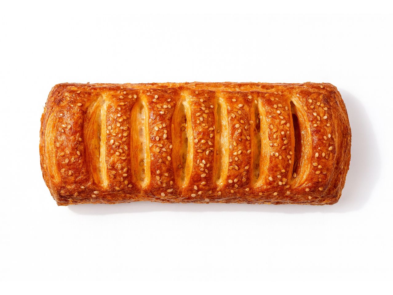 En gyllenbrun bakelse med sesamfrön på en vit bakgrund.