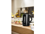 Steaming black electric kettle on a wooden counter with two glasses of fruit-infused drinks.