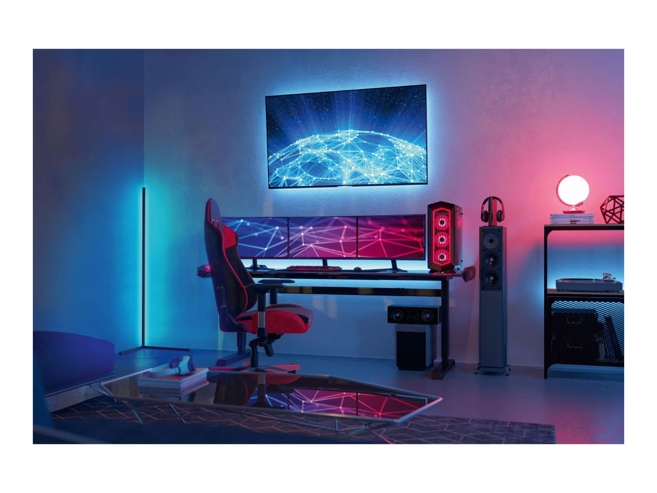 Gaming setup with a red and black gaming chair, multiple monitors, and LED lighting.
