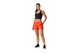 Femeie în pantaloni scurți portocalii și top negru.