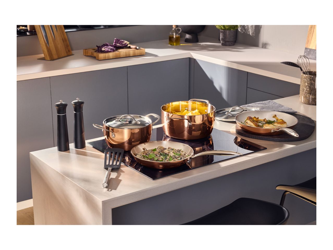 Elegant copper cookware set with pots and pans on a modern kitchen island hob.