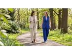 Duas mulheres com blazers ESMARA, um bege e um azul, a caminhar num parque.