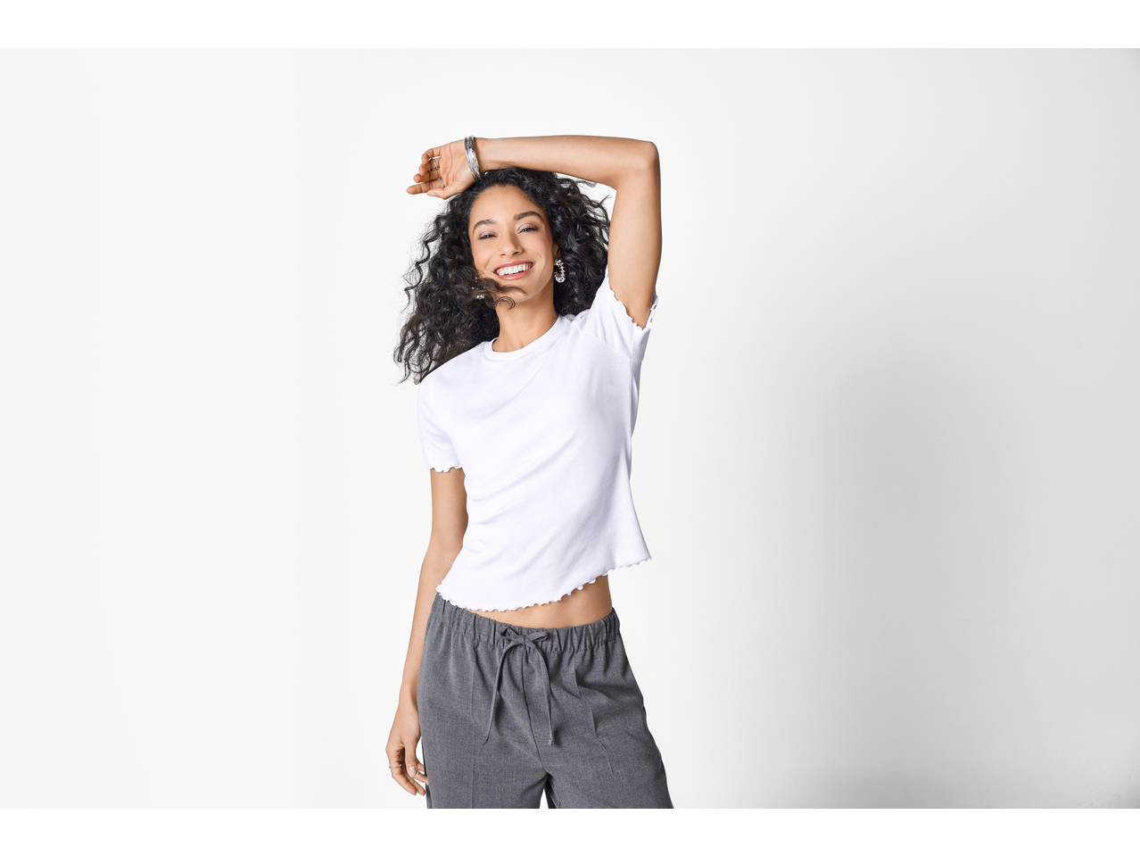 Tricou reiat ESMARA și pantaloni gri, purtate de o femeie cu păr creț.