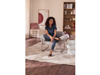 Woman in a navy polo shirt and striped trousers sitting in a living room.