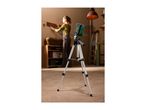 A laser level on a tripod projects a red line on a wall where a woman is hanging a shelf.