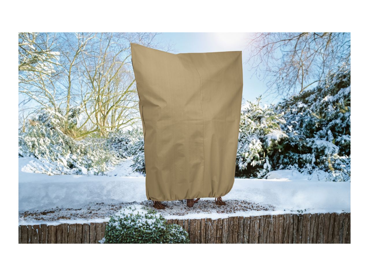 Beige winter plant protection cover on a shrub in a snowy garden.