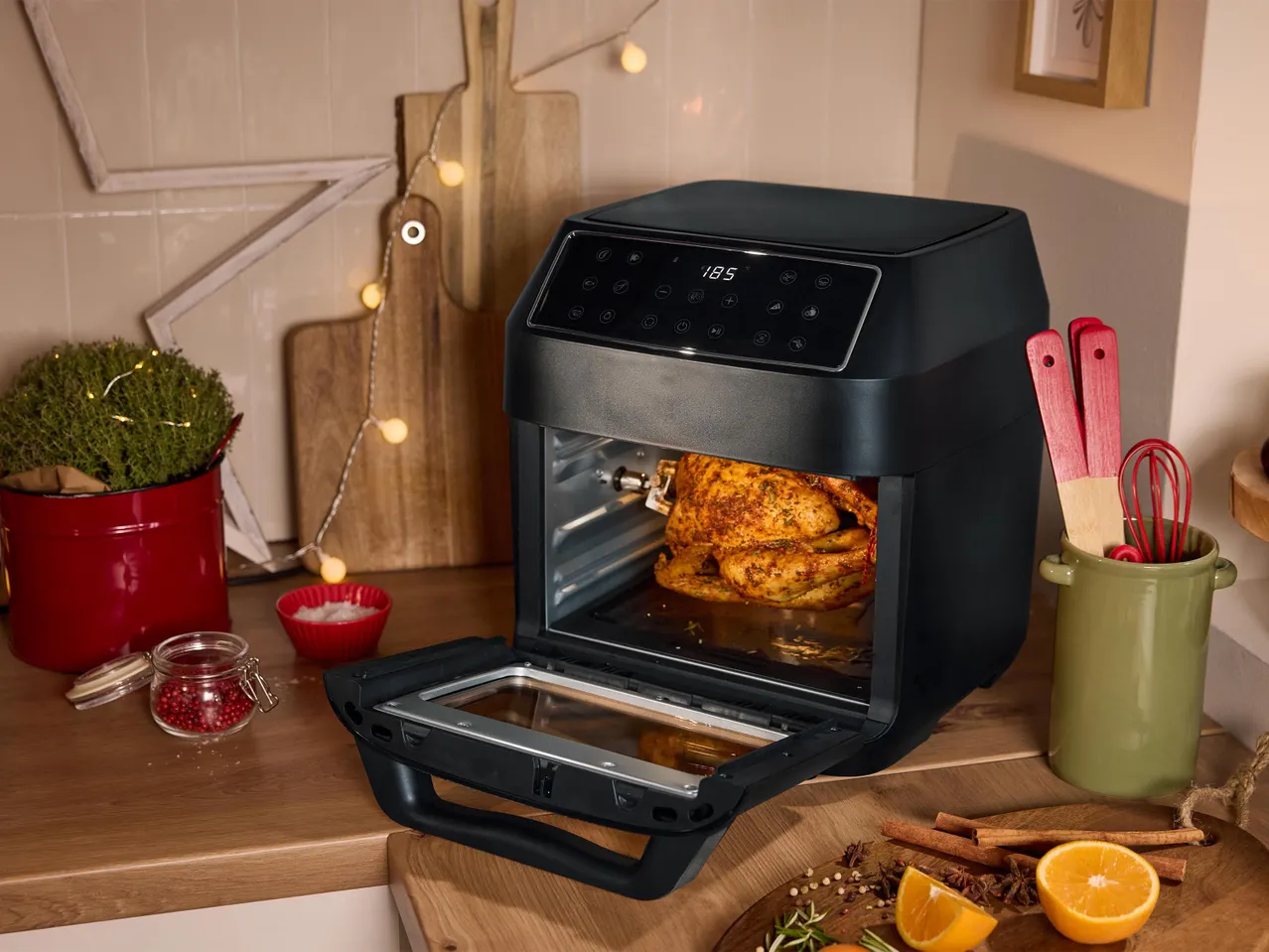 Fekete forrólevegős sütő sült csirkével, konyhai pulton, karácsonyi dekorációval.