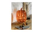 A glowing orange pumpkin decoration with small lights, surrounded by chestnuts on a wooden surface.