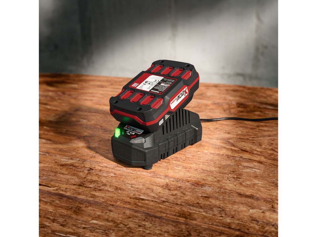 Un caricabatterie Parkside X20V Team con una batteria in carica su un tavolo di legno.