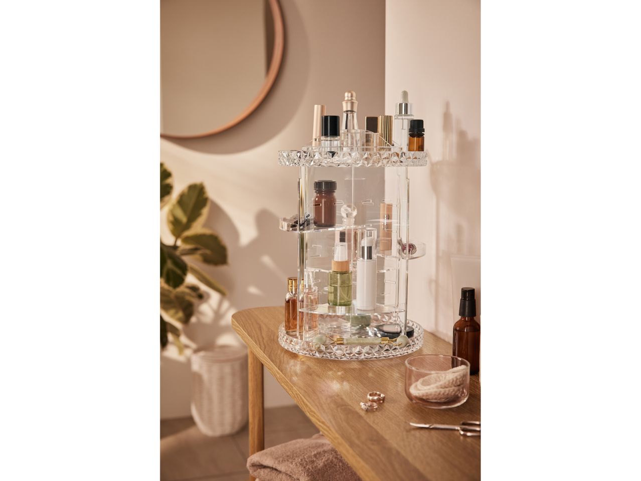 Organizzatore girevole per cosmetici in acrilico trasparente, con vari flaconi e accessori per il trucco.