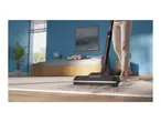 Vacuum cleaner on a rug with dirt, person in background.