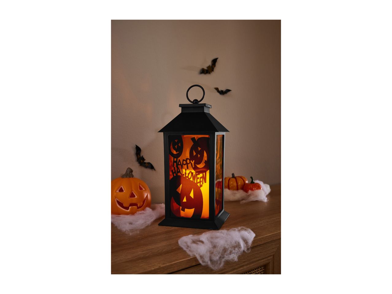 Halloween lantern with pumpkin design and spooky decorations on a wooden surface