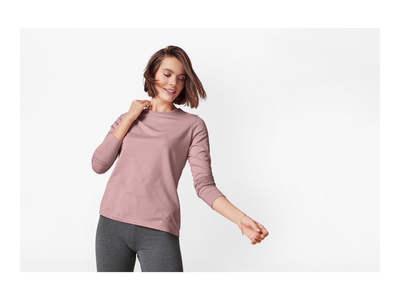 Woman in a long-sleeved pink top and dark gray leggings