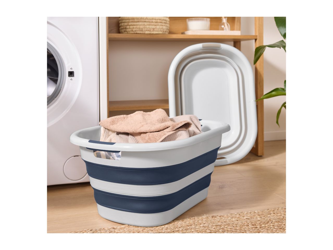 A blue and white collapsible laundry basket filled with towels, next to a washing machine.