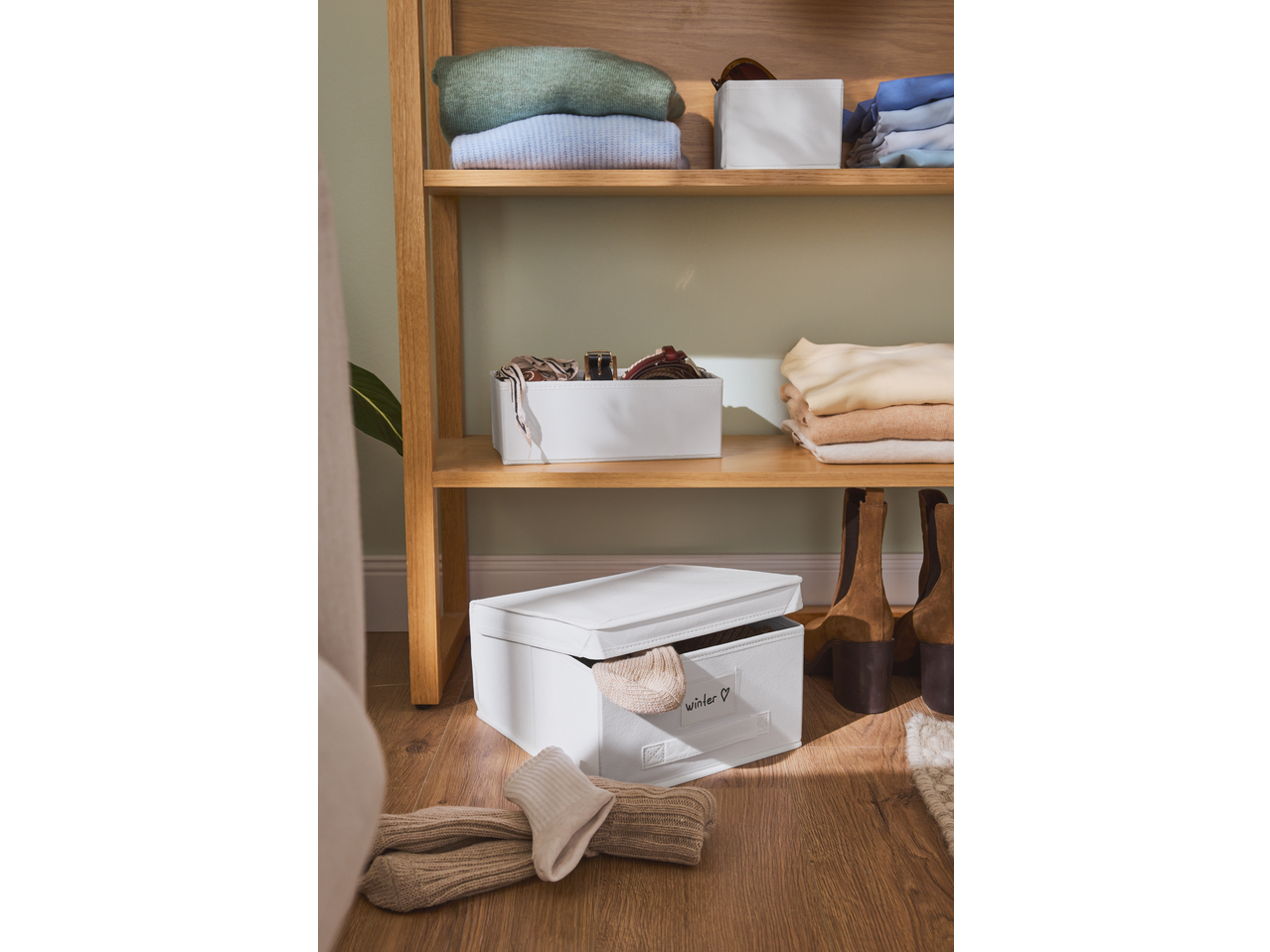 Caixas de arrumação W5 numa prateleira de madeira com roupa e acessórios.