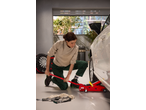 Woman using an ULTIMATE SPEED® Hydraulic Trolley Jack to lift a car in a garage.