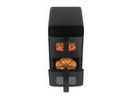 Black air fryer with a whole roasted chicken and carrots cooking inside.