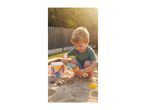 Toddler playing in a sandbox with a bucket, spade, and sand molds.