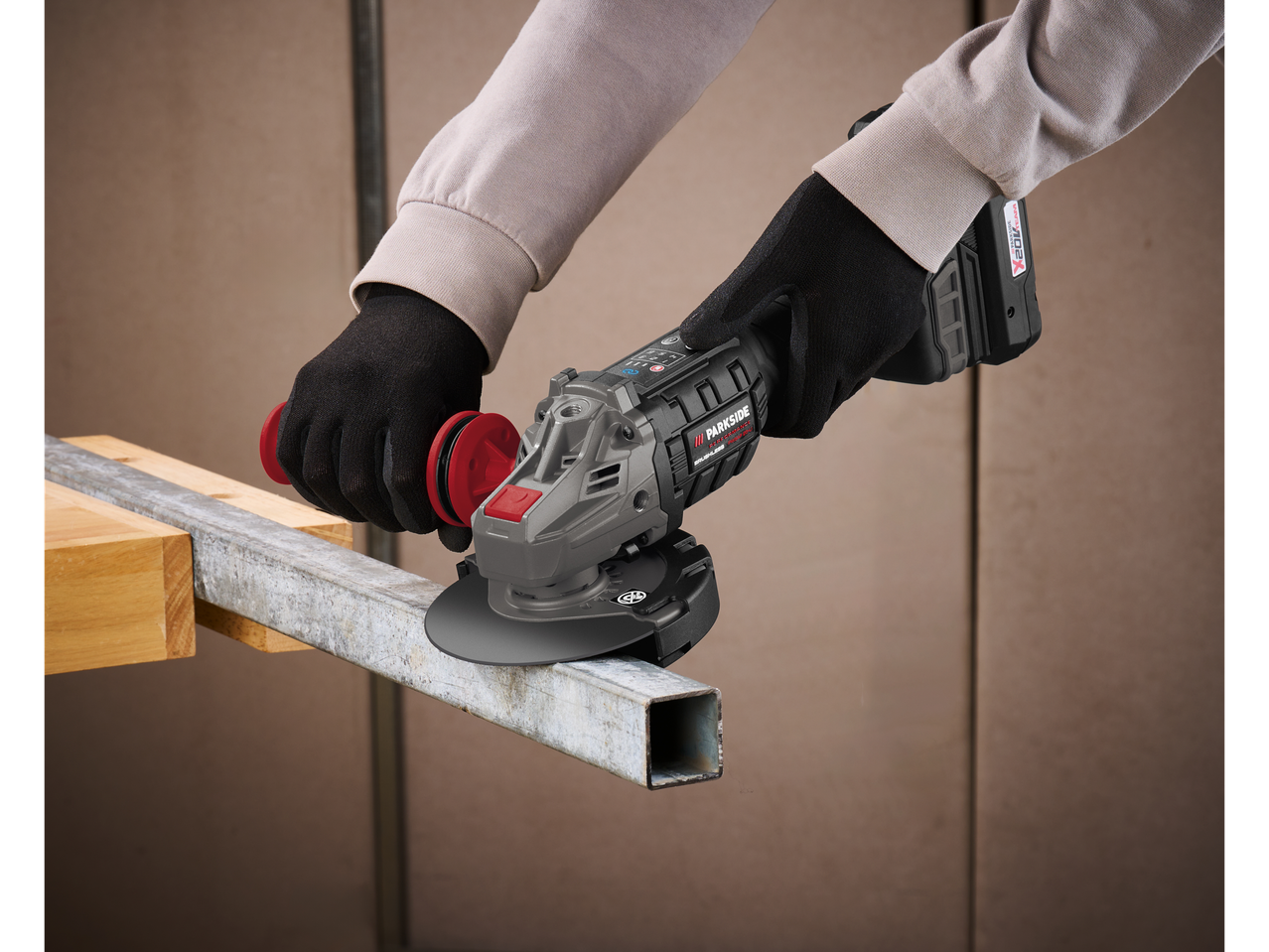 A worker uses a cordless Parkside angle grinder to work metal.