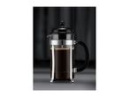 A classic glass French press filled with freshly brewed coffee on a dark background.