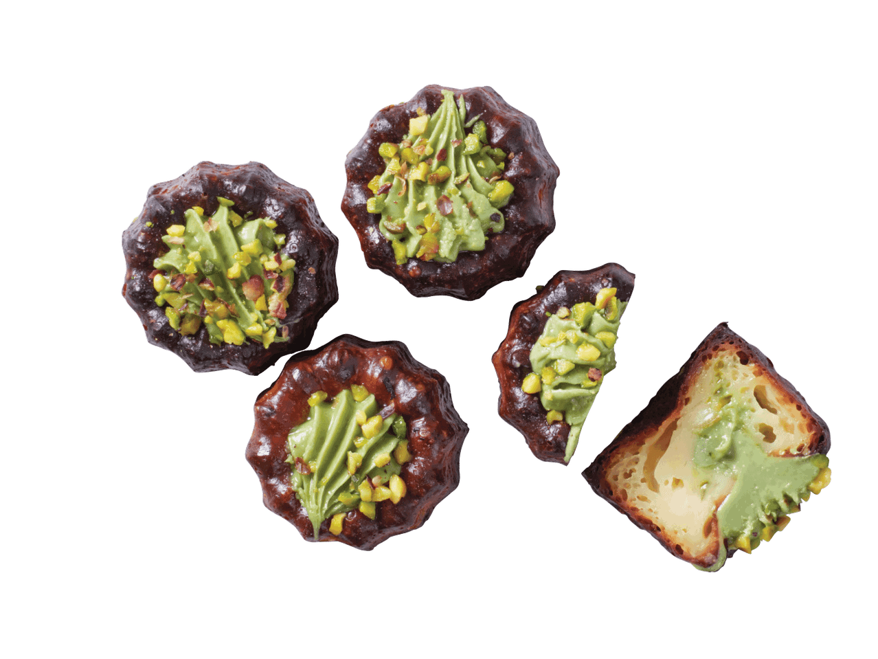 Četras šokolādes kūciņas ar zaļu krēmu un pistācijām, viena kūciņa pārgriezta uz pusēm.