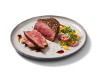 Steak de bœuf tranché avec une salade fraîche de légumes et d'oignons rouges.