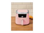 Pink air fryer with a digital display on a wooden surface next to a bowl of fries.