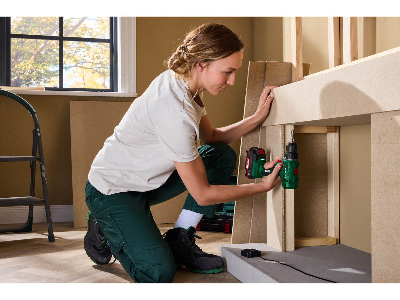 Frau montiert Möbel mit einem Akku-Bohrschrauber.