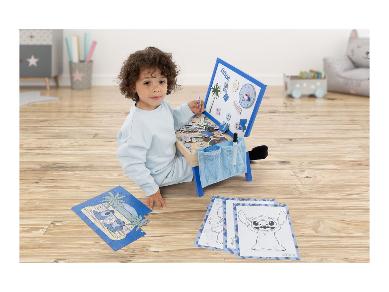A child playing with a magnetic board and puzzle featuring cartoon characters, surrounded by coloring pages.