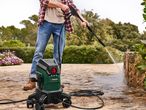 A person uses a Bosch pressure washer to clean a patio.