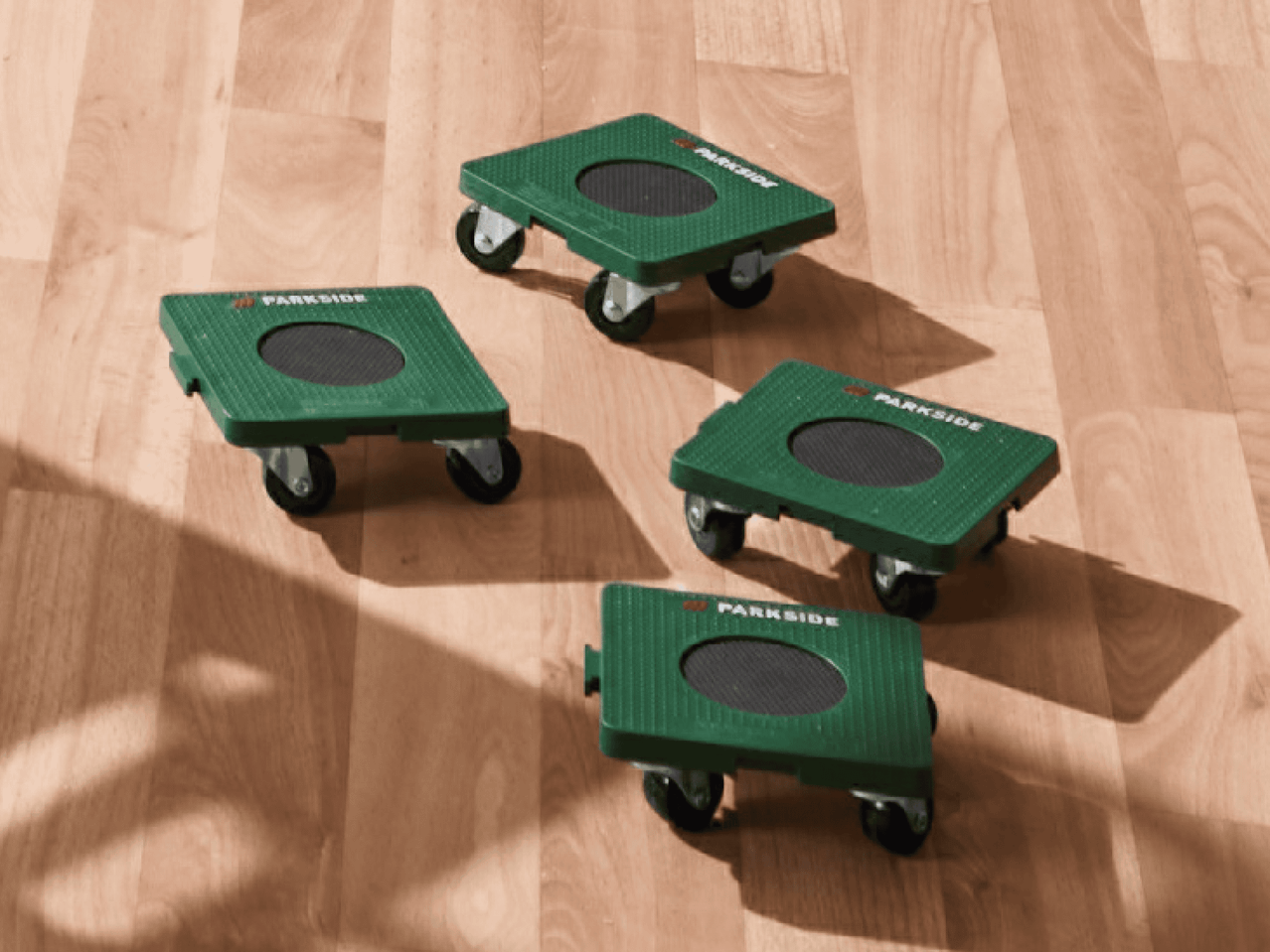 Vier grüne Parkside Rollbretter auf einem Holzboden