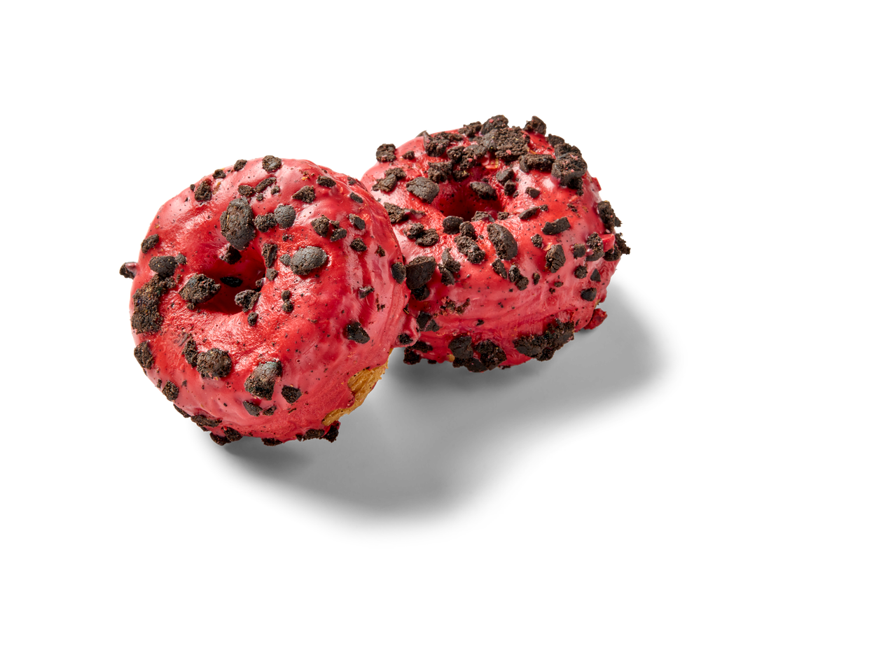 Twee rode cronuts met koekjeskruimels op een zwarte achtergrond.