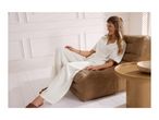 Woman in white loungewear sitting on a brown armchair next to a wooden side table.