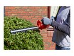 Person trimming a green hedge with a red electric hedge trimmer.