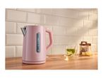 Pink electric kettle on a wooden counter with tea and lemons in the background.
