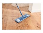 Blue flat mop cleaning spilled water on a wooden floor next to a round rug.