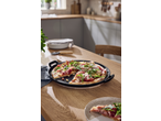 Pizza servida numa placa de ferro fundido SILVERCREST numa mesa de cozinha.
