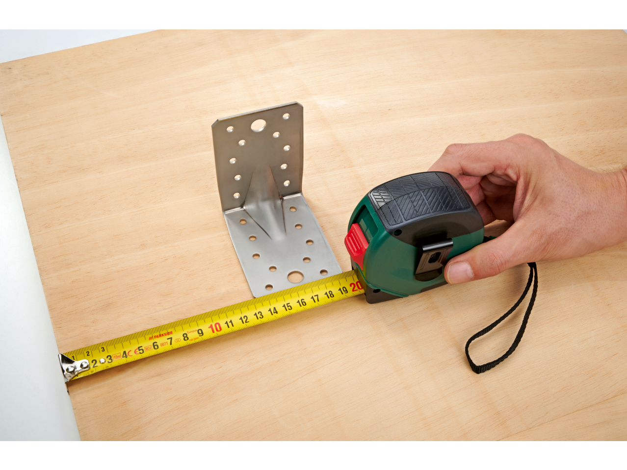 PARKSIDE: Măsurarea unei console metalice cu o ruletă pe o placă de lemn.