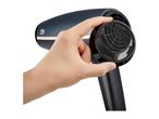 A hand holding a dark grey hairdryer, showing the removable honeycomb filter at the back.