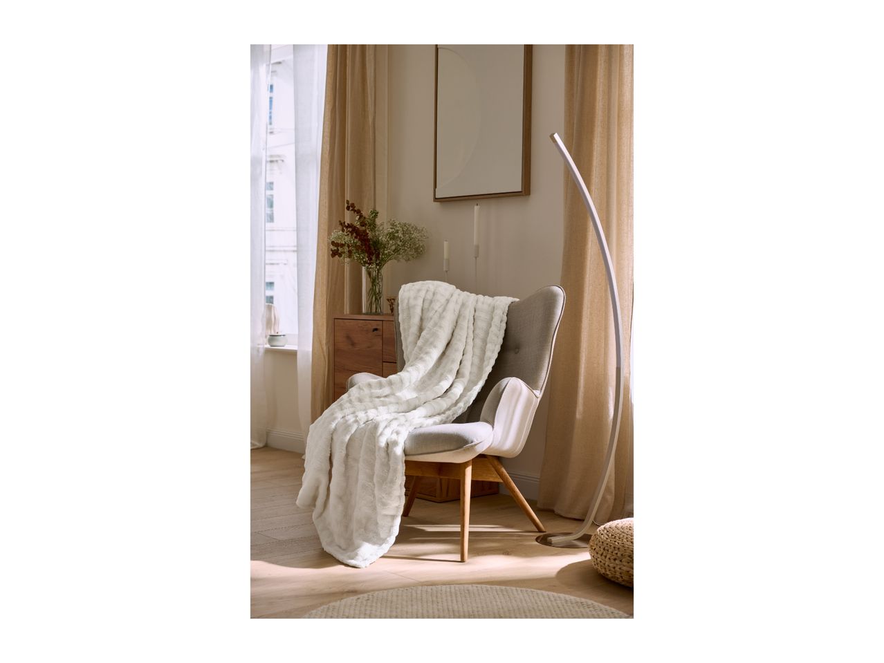 Cozy reading corner with a grey armchair, white blanket, and modern floor lamp.