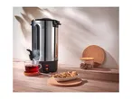 SilverCrest hot water dispenser with a cup of tea and cookies on a wooden table.