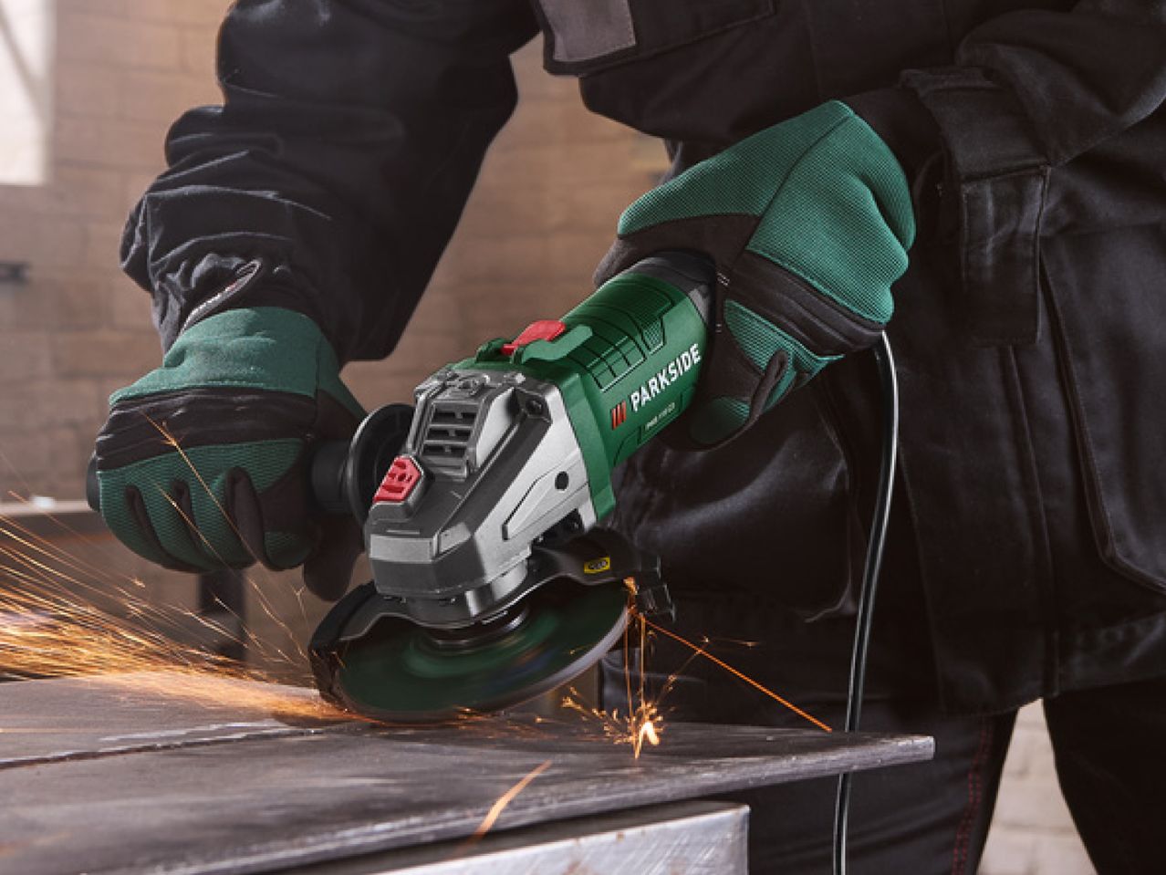 Person in work gloves using an angle grinder to cut metal, creating sparks.