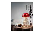 A mushroom-shaped lamp with red cap and sparkling base, next to a bowl of cookies.