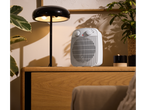 TRONIC® 2000W Fan Heater on a wooden cabinet, next to a lamp and plants.