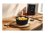 Air fryer with a bowl of crinkle-cut fries on a wooden countertop.