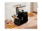 A black electric meat grinder extruding dough, with flour, an egg, and cookies on a wooden counter.