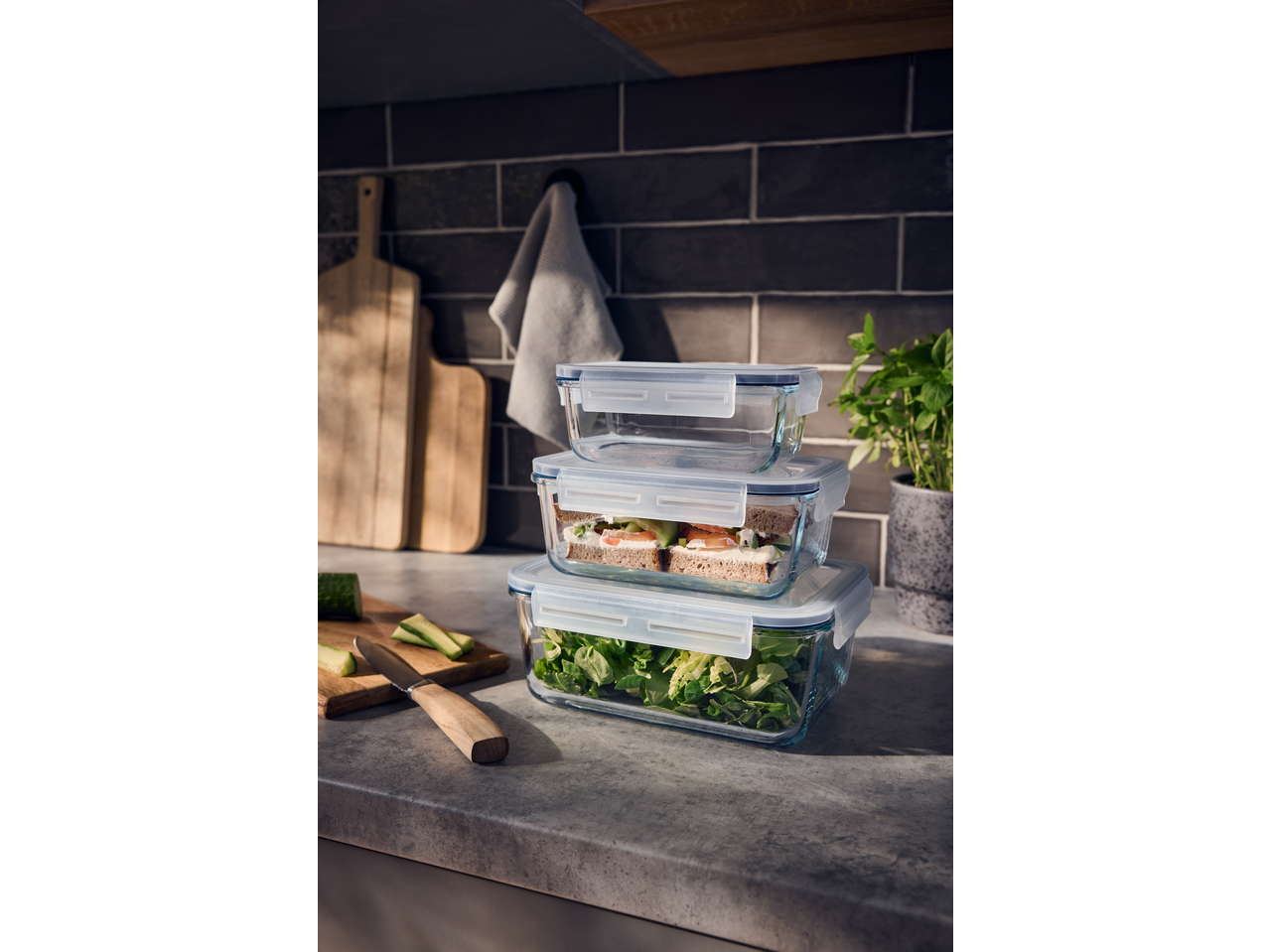 Cutii de depozitare Silvercrest® stivuite cu salată și sandvișuri pe un blat de bucătărie.