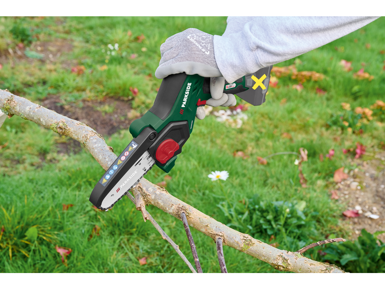 Mini fierăstrău cu lanț PARKSIDE tăind o creangă de copac.